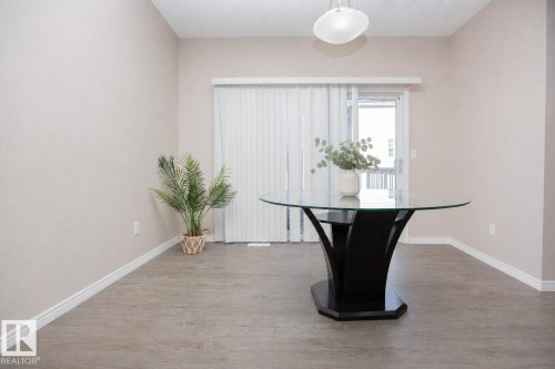 Spacious room featuring wood-finish flooring, light-colored walls, white baseboards, and a glass-paneled sliding door - 8 Meadowlink Common, Spruce Grove, AB 