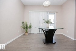 Spacious room featuring wood-finish flooring, light-colored walls, white baseboards, and a glass-paneled sliding door - 