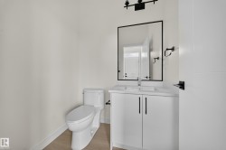 Contemporary bathroom featuring a white vanity with a rectangular undermount sink, a quartz-finish countertop, and black hardware - 
