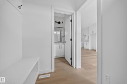 Entryway featuring a built-in bench and coat hooks, with wood-finish flooring extending into adjacent rooms - 