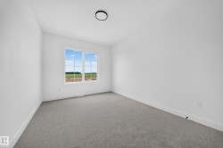 Spacious room featuring light gray carpeting, crisp white walls, and a large window with white framing - 