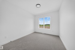 Bright room featuring a large window with white framing and muntins, gray carpet, white baseboards, and a contemporary ceiling light fixture - 