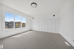 Spacious room featuring a large triple-pane window, board and batten wall accent, neutral carpeting, white trim, and a contemporary flush-mount ceiling light - 