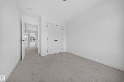 Carpeted room with white walls, baseboards, and double-door closet featuring matte black hardware - 