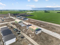 Developing residential neighborhood with new construction homes, paved streets, and expansive green fields bordering the community - 