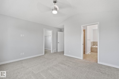 Spacious room featuring light gray carpeting, vaulted ceiling with a modern ceiling fan, and light gray wall paint - 614 Mcdonough Link, Edmonton, AB 