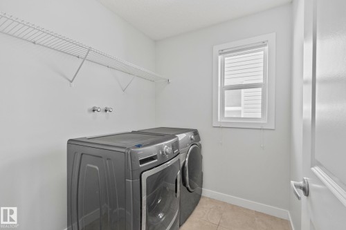 Dedicated laundry area featuring a wire shelf for storage, wall-mounted connections, and a window with blinds - 614 Mcdonough Link, Edmonton, AB 