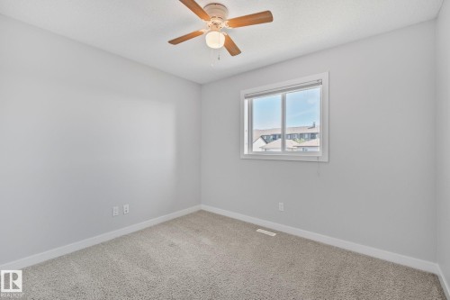 Carpeted room with a ceiling fan, a window, light gray walls, and white trim - 614 Mcdonough Link, Edmonton, AB 