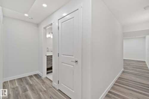 Hallway with wood-finish flooring, recessed lighting, and white baseboards - 614 Mcdonough Link, Edmonton, AB 