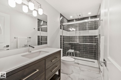 Contemporary bathroom featuring a wood-finish vanity with an integrated sink and chrome faucet - 614 Mcdonough Link, Edmonton, AB 