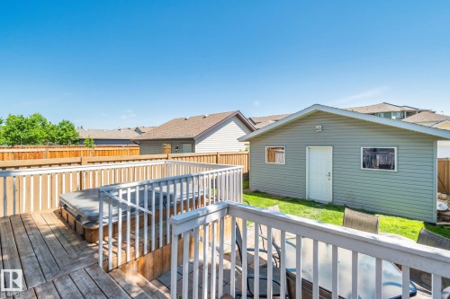 Wooden deck featuring a built-in hot tub, white railing, and a separate detached outbuilding with siding - 614 Mcdonough Link, Edmonton, AB 