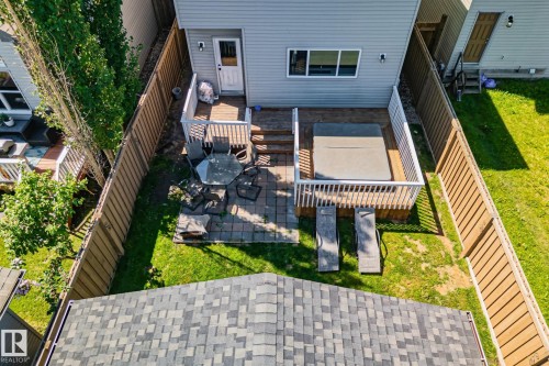 Expansive backyard featuring a multi-level wooden deck with white railing, integrated hot tub, and two sun loungers - 614 Mcdonough Link, Edmonton, AB 