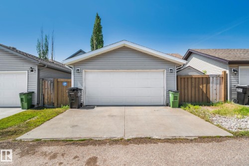 Two-car garage with light gray siding, white garage door, and concrete driveway - 614 Mcdonough Link, Edmonton, AB 