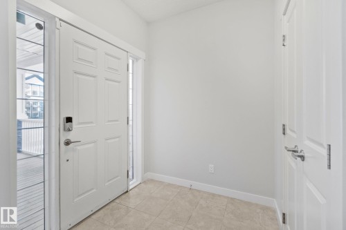 Front entry with light-toned tiled flooring, a paneled door, and a digital lock - 614 Mcdonough Link, Edmonton, AB 