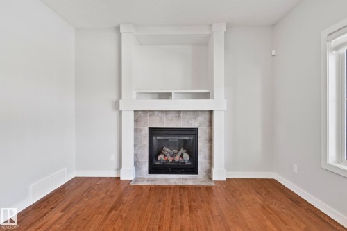 Fireplace with stone tile surround, integrated shelving, and white mantel - 614 Mcdonough Link, Edmonton, AB 