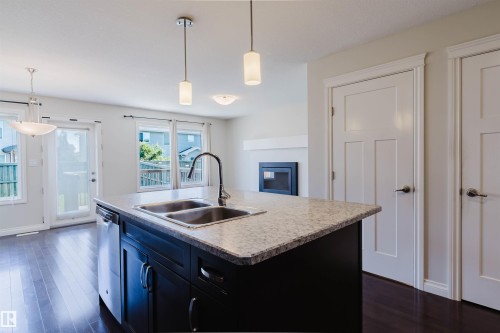 Kitchen island featuring a double-basin sink and integrated dishwasher - 1131 177 Street, Edmonton, AB 