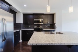 Kitchen featuring wood-finish flooring, dark cabinetry with stainless steel hardware, and a subway tile backsplash - 