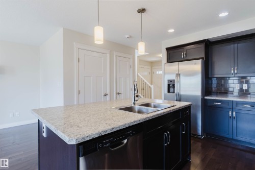 Kitchen island with a double basin stainless steel sink and granite countertop - 1131 177 Street, Edmonton, AB 