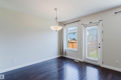 Hardwood-finish flooring highlights this room with a contemporary semi-flush pendant light fixture - 1131 177 Street, Edmonton, AB 