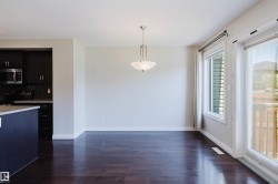 Open concept living space featuring dark wood-finish flooring, a contemporary chandelier, and a sliding glass door providing exterior access - 
