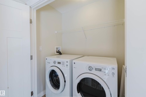 Dedicated laundry area featuring front-loading appliances, a wire shelf, and light-toned walls - 1131 177 Street, Edmonton, AB 