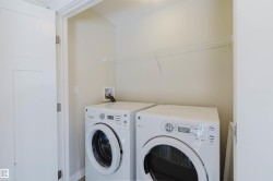 Dedicated laundry area featuring front-loading appliances, a wire shelf, and light-toned walls - 
