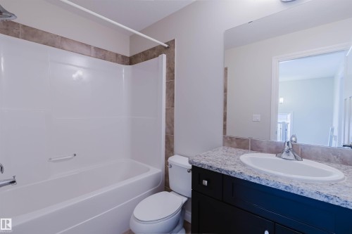 Bathroom featuring a built-in tub with a white surround and a tiled accent border - 1131 177 Street, Edmonton, AB 