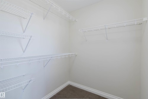 Walk-in closet featuring white wire shelving units and wall-to-wall carpeting - 1131 177 Street, Edmonton, AB 