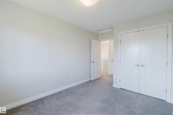 Bedroom featuring a neutral wall color, gray carpeting, a flush mount ceiling light fixture, and white panel doors with brushed nickel hardware - 