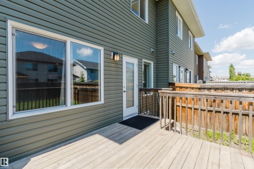 Expansive wooden deck with natural wood railing, dark green vinyl siding, and white-framed windows - 1131 177 Street, Edmonton, AB 