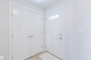 Entryway featuring a white paneled door with transom windows, a double-door closet with satin nickel hardware, and light-toned flooring - 1131 177 Street, Edmonton, AB 