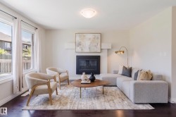 Living area featuring dark wood-finish flooring, a fireplace with a black insert, white baseboards, and multiple windows providing natural light - 