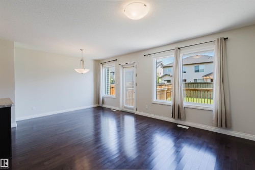 Spacious room featuring dark wood-finish flooring, light neutral wall paint, and white trim - 1131 177 Street, Edmonton, AB 