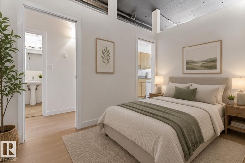 Bedroom featuring light wood-finish flooring, white walls, and an exposed concrete ceiling with industrial piping - 404 10024 Jasper Avenue, Edmonton, AB 