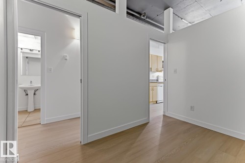 Light wood-finish flooring extending throughout, complemented by white walls and trim - 404 10024 Jasper Avenue, Edmonton, AB 