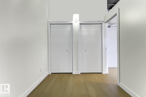Hallway with light wood-finish flooring, white walls, and bright white trim - 404 10024 Jasper Avenue, Edmonton, AB 