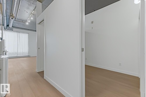 Interior hallway featuring light wood-finish flooring and crisp white walls - 404 10024 Jasper Avenue, Edmonton, AB 