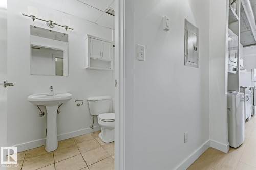 White pedestal sink with a rectangular mirror and white vanity light fixture - 404 10024 Jasper Avenue, Edmonton, AB 