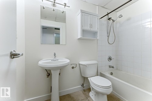 Bathroom featuring a pedestal sink, wall-mounted mirror, and a white tile shower with a bathtub - 404 10024 Jasper Avenue, Edmonton, AB 