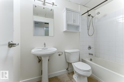Bathroom featuring a pedestal sink, wall-mounted mirror, and a white tile shower with a bathtub - 