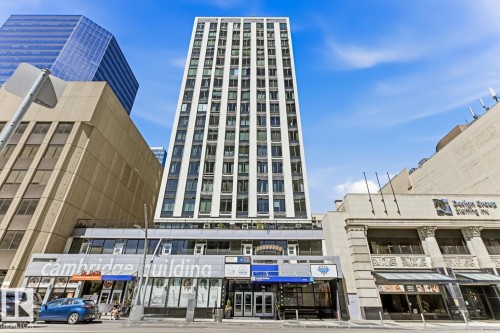 Tall commercial building with a white facade and numerous windows, featuring a lower level with retail storefronts - 404 10024 Jasper Avenue, Edmonton, AB 
