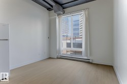 Bright interior featuring wood-finish flooring, a large window, white walls, and exposed ductwork - 