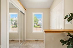 Entryway featuring two windows, mirrored sliding closet doors, a paneled entry door, and tiled flooring - 
