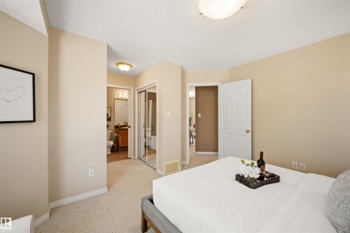 Neutral tone walls with white trim, soft carpeting, and a built-in closet with mirrored sliding doors - 7838 Schmid Place Nw, Edmonton, AB 
