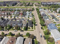 Residential street with established homes featuring varied architectural styles and pitched roofs - 