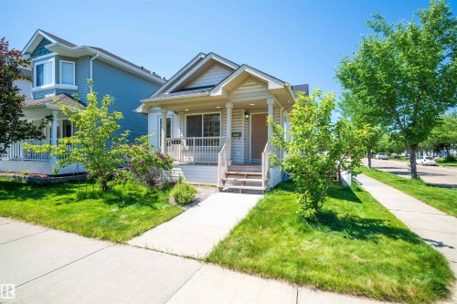 Cream-colored siding home featuring a covered front porch with white railings and columns - 7838 Schmid Place Nw, Edmonton, AB 