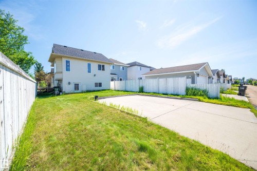 Expansive paved surface with ample grass border, featuring a white privacy fence - 7838 Schmid Place Nw, Edmonton, AB 