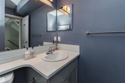 Bathroom featuring a built-in sink, light-toned countertop, and grey base cabinetry with chrome hardware - 