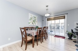 Dining area featuring light wood-finish flooring, light gray walls, and a contemporary pendant light fixture - 