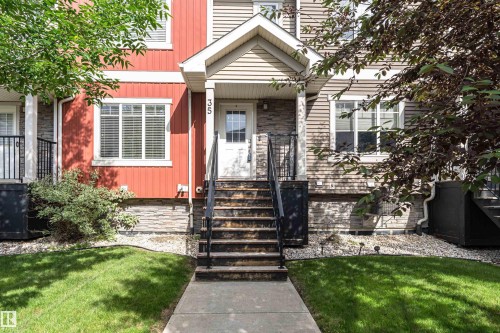 Multi-level townhouse entrance featuring a white paneled door, stone facade accents, and horizontal siding - 35 675 Albany Way, Edmonton, AB 